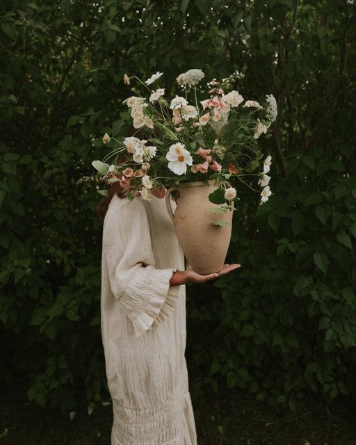 Woman carrying a large clay vessel full of flowers